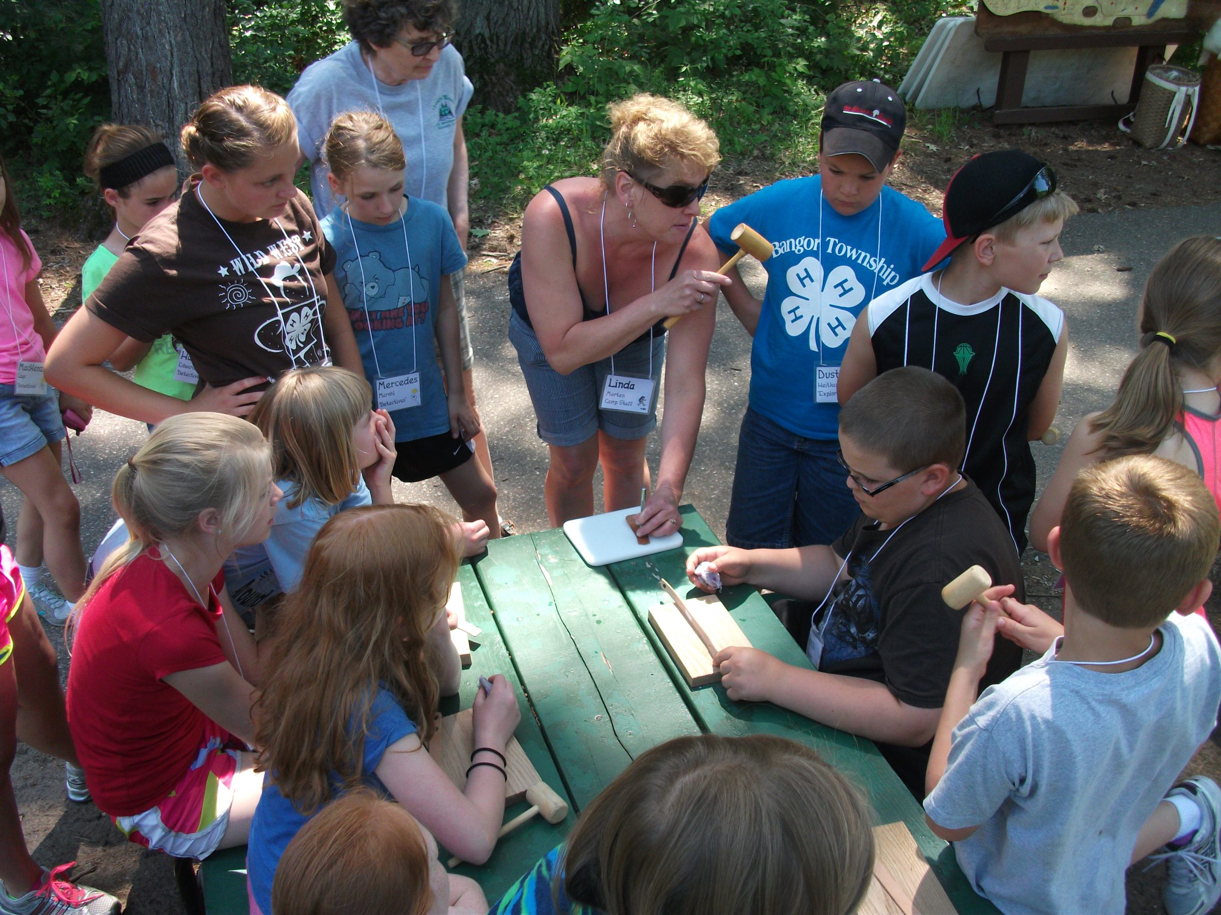 A group of youth listening at a picnic table while a volunteer instructs.