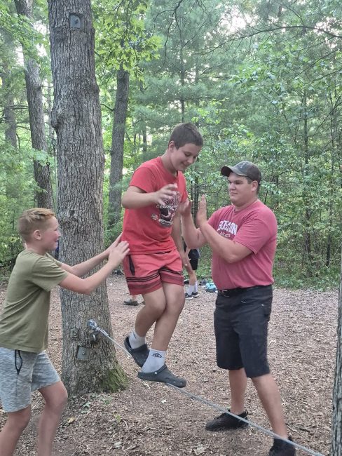youth and chaperone at camp trying to walk the ropes course.